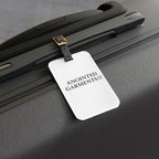 Anointed Garments white acrylic luggage tag with a black leather strap attached to a grey suitcase.