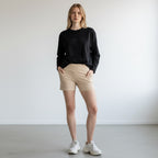 Model wearing Anointed Garments high-waisted beige athletic performance shorts with side pockets and crossover waistband
