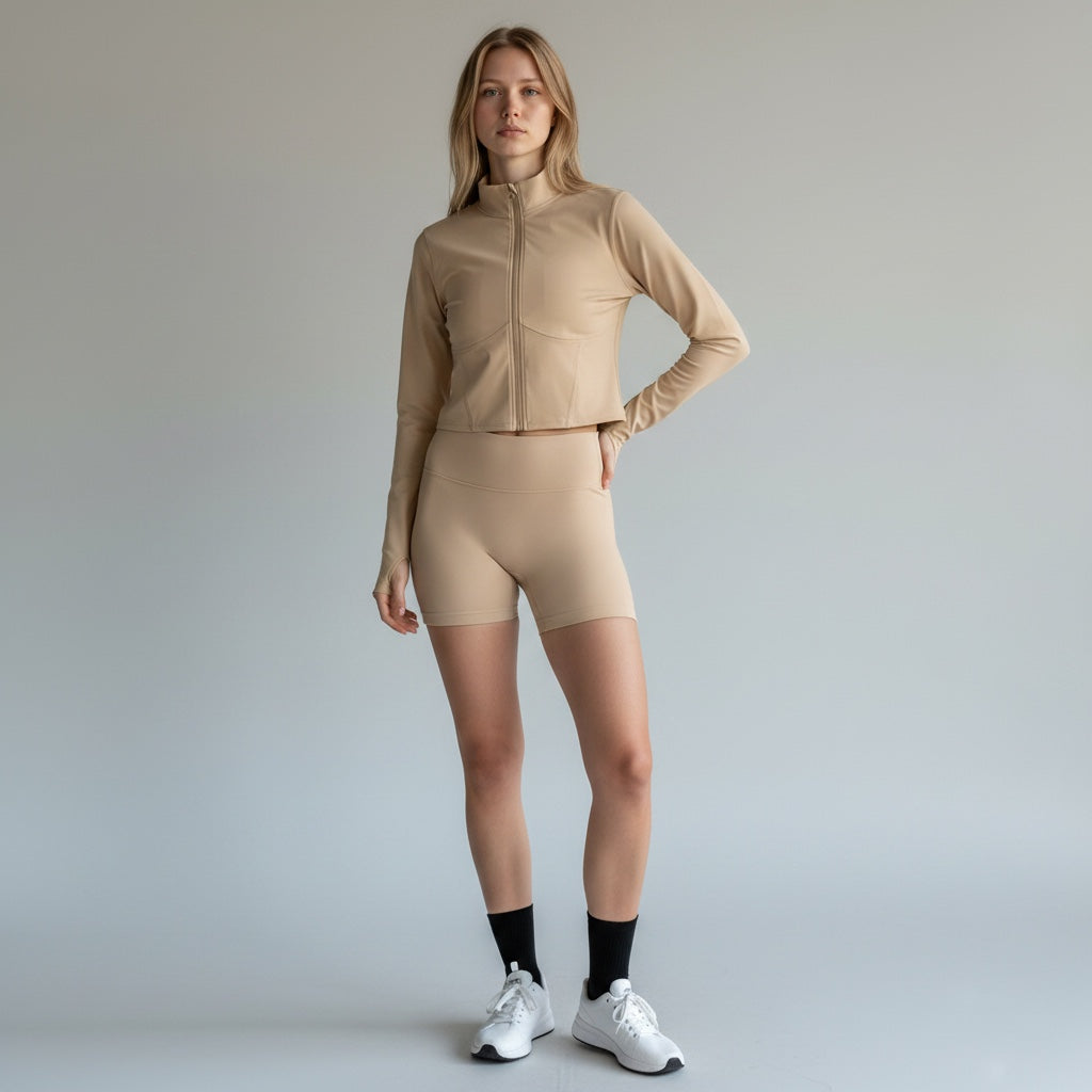 Model wearing Anointed Garments beige cropped long sleeve mock neck zip up jacket with matching athletic shorts.