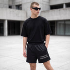 Anointed Garments unisex athletic shorts in black with white logo, worn by a man in a black t-shirt and sunglasses.