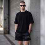 Anointed Garments unisex athletic shorts in black with white logo, worn by a man in a black t-shirt and sunglasses.
