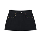 Anointed Garments black denim mini skirt with an A-line silhouette and polished gold-tone stud hardware details.