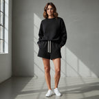 Woman wearing Anointed Garments black fleece lounge shorts with a drawstring waist and matching sweatshirt.