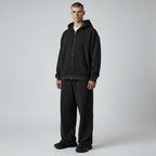 Model wearing an Anointed Garments Essential black full zip hoodie and matching sweatpants in a relaxed fit.