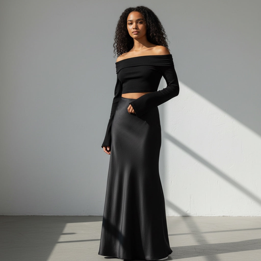 Anointed Garments black off-the-shoulder long sleeve crop top with flared cuffs worn by a model with a satin skirt.