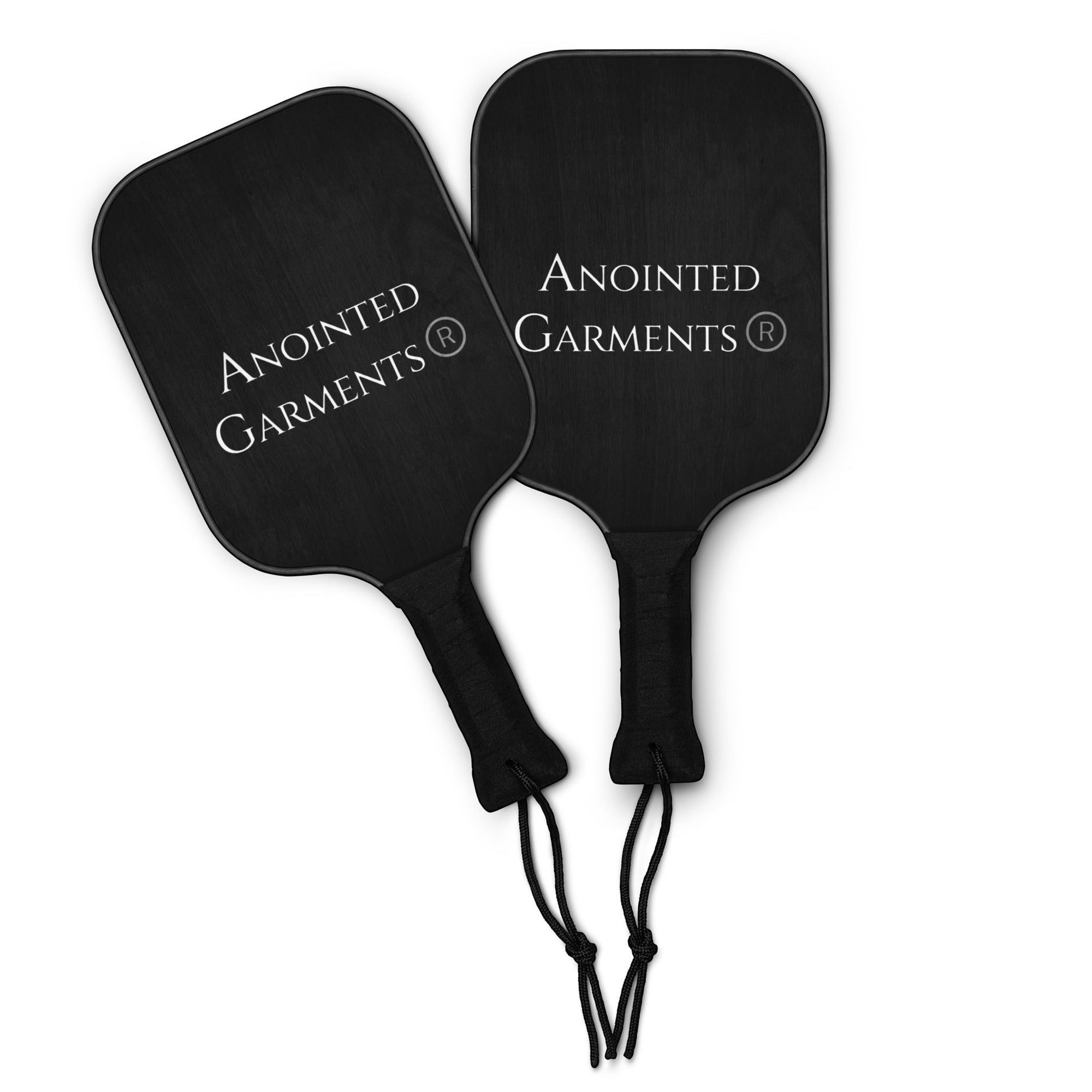 Anointed Garments pickleball paddle set featuring two black wooden paddles with white logo branding and wrist straps.