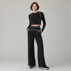 Anointed Garments high-waisted black wide-leg trousers with white contrast piping worn by a model with a matching top.