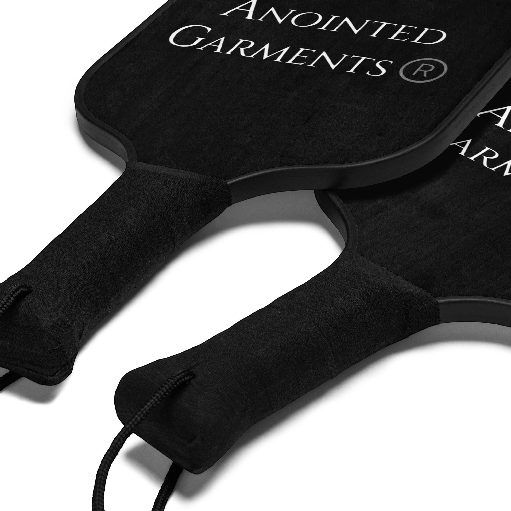 Anointed Garments pickleball paddle set featuring two black wooden paddles with comfortable poly-cotton handle grips.