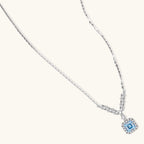 Anointed Garments Celestial Arc necklace in platinum-plated sterling silver with a blue moissanite V-shaped pendant.