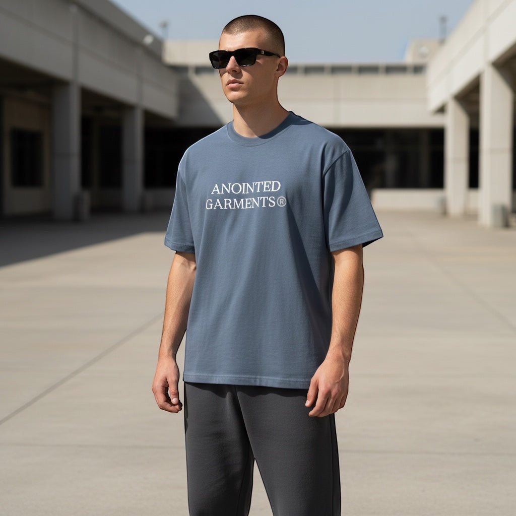Anointed Garments blue oversized cotton t-shirt with white chest logo worn by a man in sunglasses outdoors