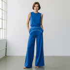 A woman wearing Anointed Garments blue high-waisted wide-leg trousers with white contrast piping and a matching tank top.