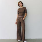 Anointed Garments brown high-waisted wide-leg trousers with white contrast piping worn by a woman with a matching top.