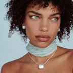 Anointed Garments brushed sterling silver disc necklace worn by a model with curly hair and a light blue neck scarf.