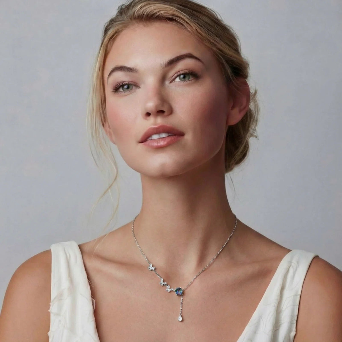 Anointed Garments Butterfly Dreams necklace featuring three silver butterflies and a rainbow moissanite on a woman.