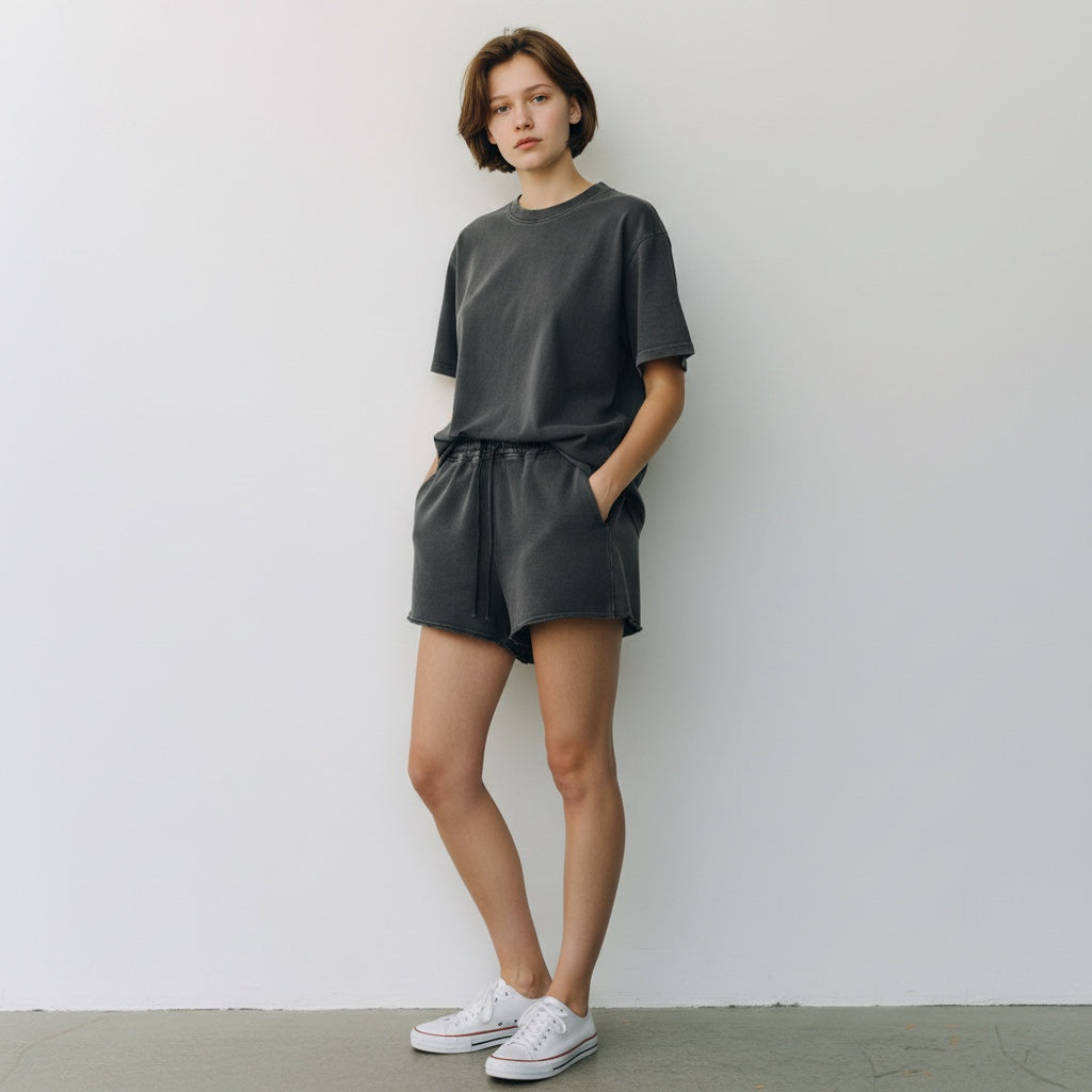 Woman wearing Anointed Garments charcoal grey cotton fleece lounge shorts with raw-edge hem and matching t-shirt.