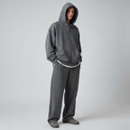 A model wearing an Anointed Garments charcoal grey full zip hoodie and matching sweatpants in a studio setting.