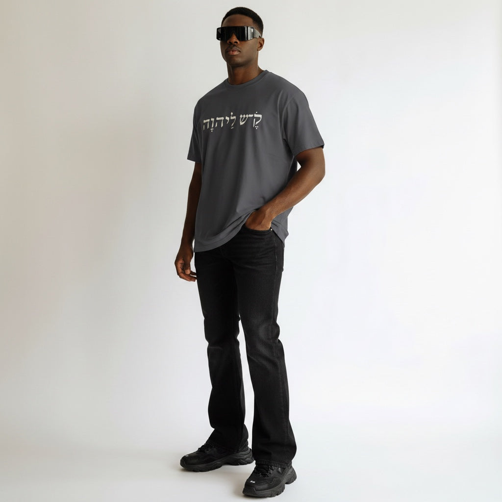 Anointed Garments charcoal gray cotton t-shirt with white Hebrew script graphic worn by a man in sunglasses