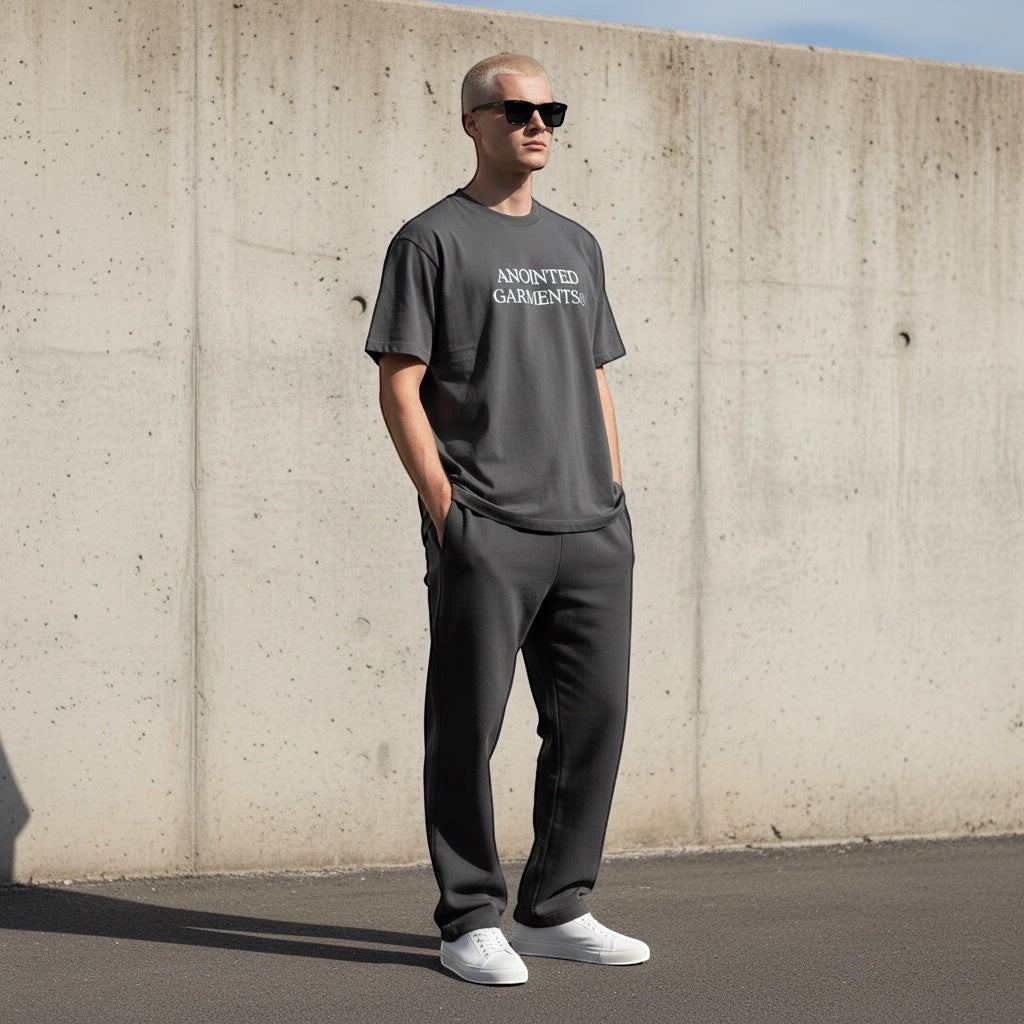 Model wearing an Anointed Garments charcoal grey oversized cotton t-shirt with logo, paired with matching joggers.