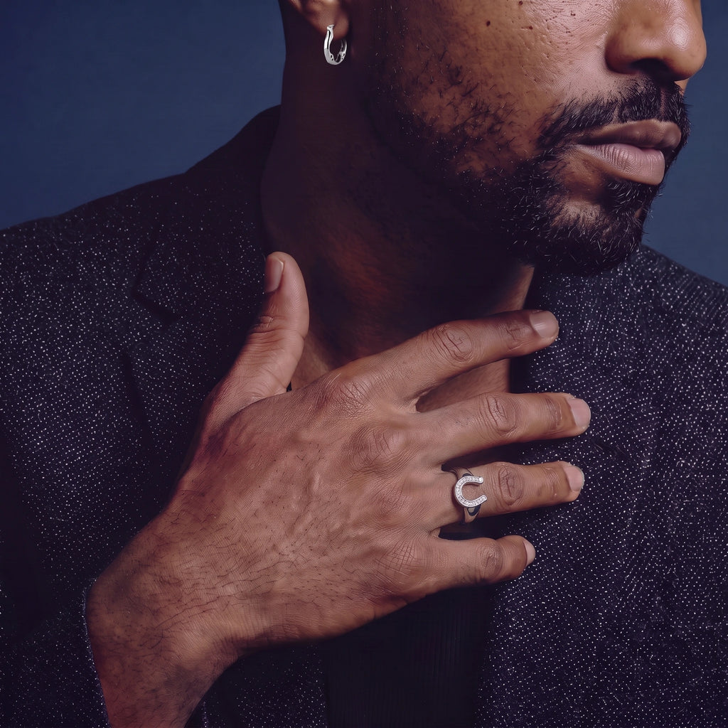 Anointed Garments sterling silver clover hoop earring worn on a man's ear against a dark blue background.