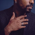 Anointed Garments sterling silver clover hoop earring worn on a man's ear against a dark blue background.