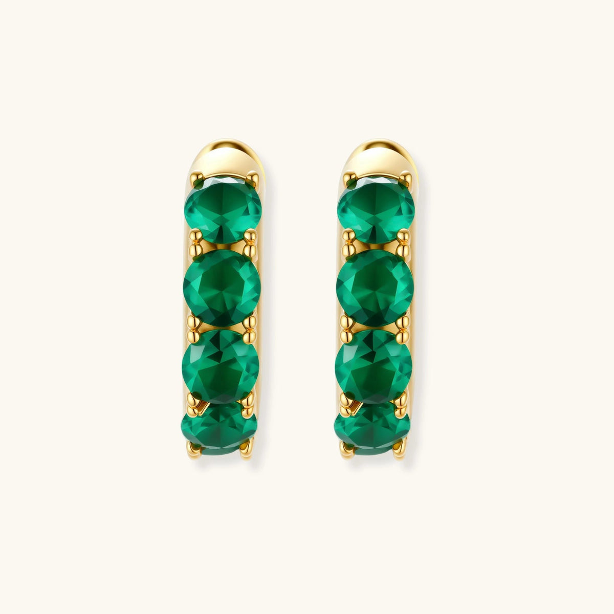 Anointed Garments emerald huggie hoops in 18K gold-plated sterling silver with round green cubic zirconia stones.