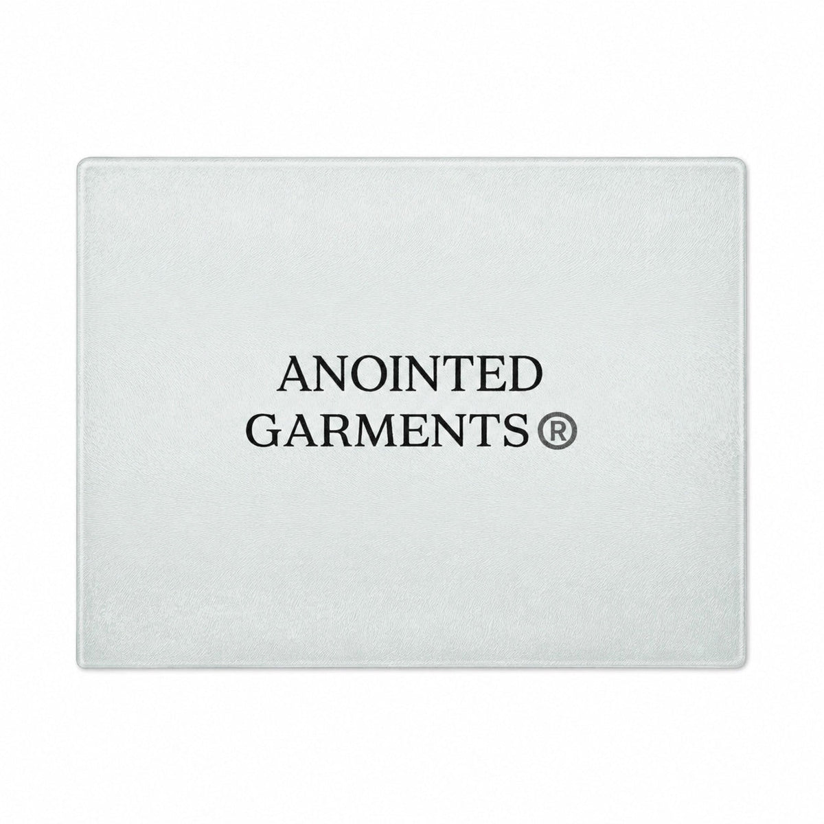 Anointed Garments tempered glass cutting board with a whorled texture and centered brand logo on a white background.