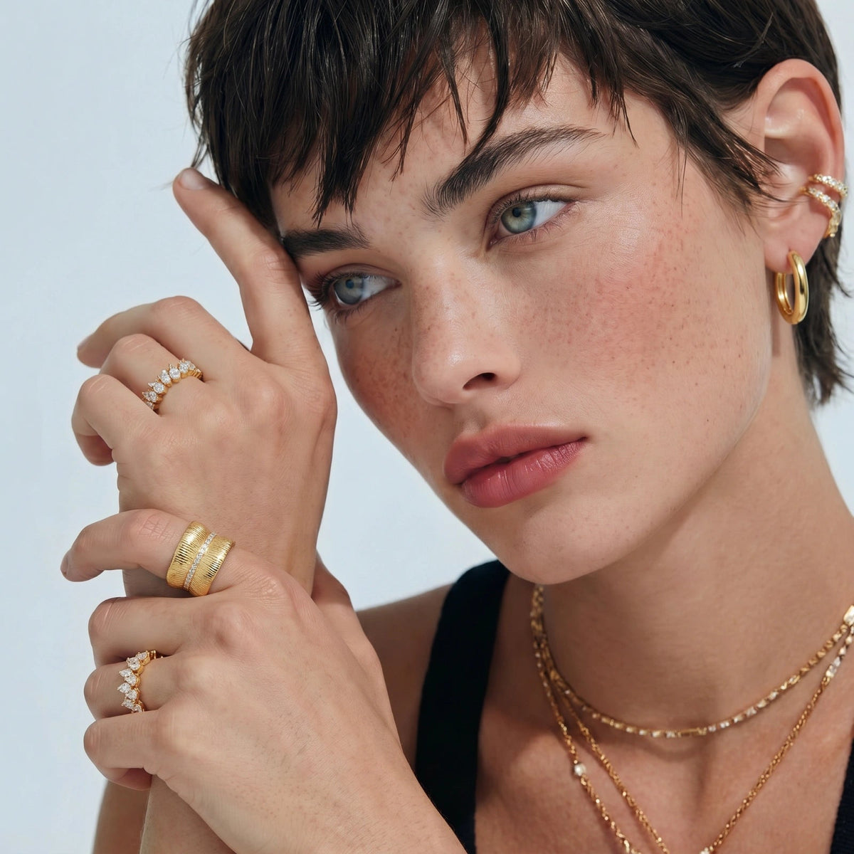 Anointed Garments 14K gold-plated sterling silver hoop earrings worn by a model with layered rings and necklaces