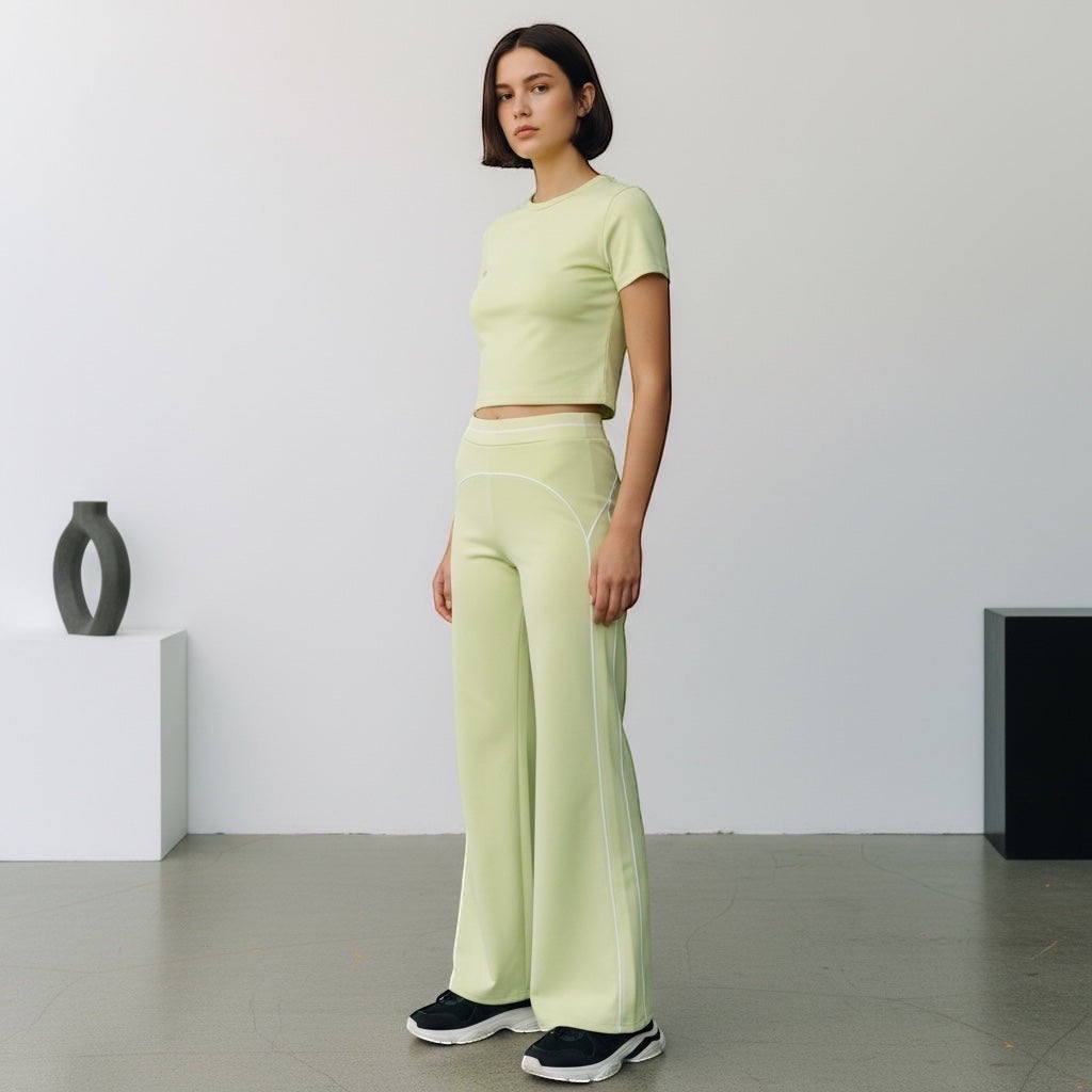 Model wearing Anointed Garments light green high-waisted wide-leg trousers with white piping and matching crop top