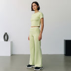 Model wearing Anointed Garments light green high-waisted wide-leg trousers with white piping and matching crop top