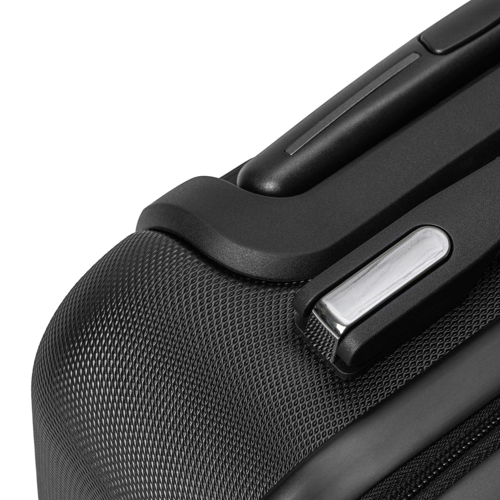 Anointed Garments hardshell travel suitcase corner detail showing textured black polycarbonate and metallic accents.