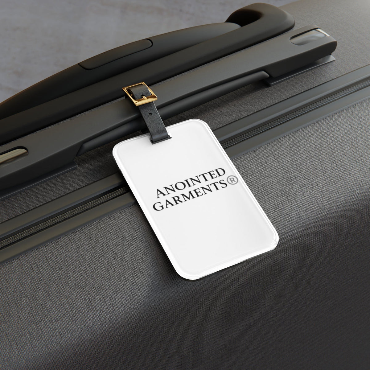 Anointed Garments hardshell suitcase featuring a white luggage tag with the brand logo attached to the handle.