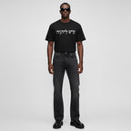 Model wearing Anointed Garments black cotton t-shirt with white Hebrew script graphic, styled with dark denim jeans.