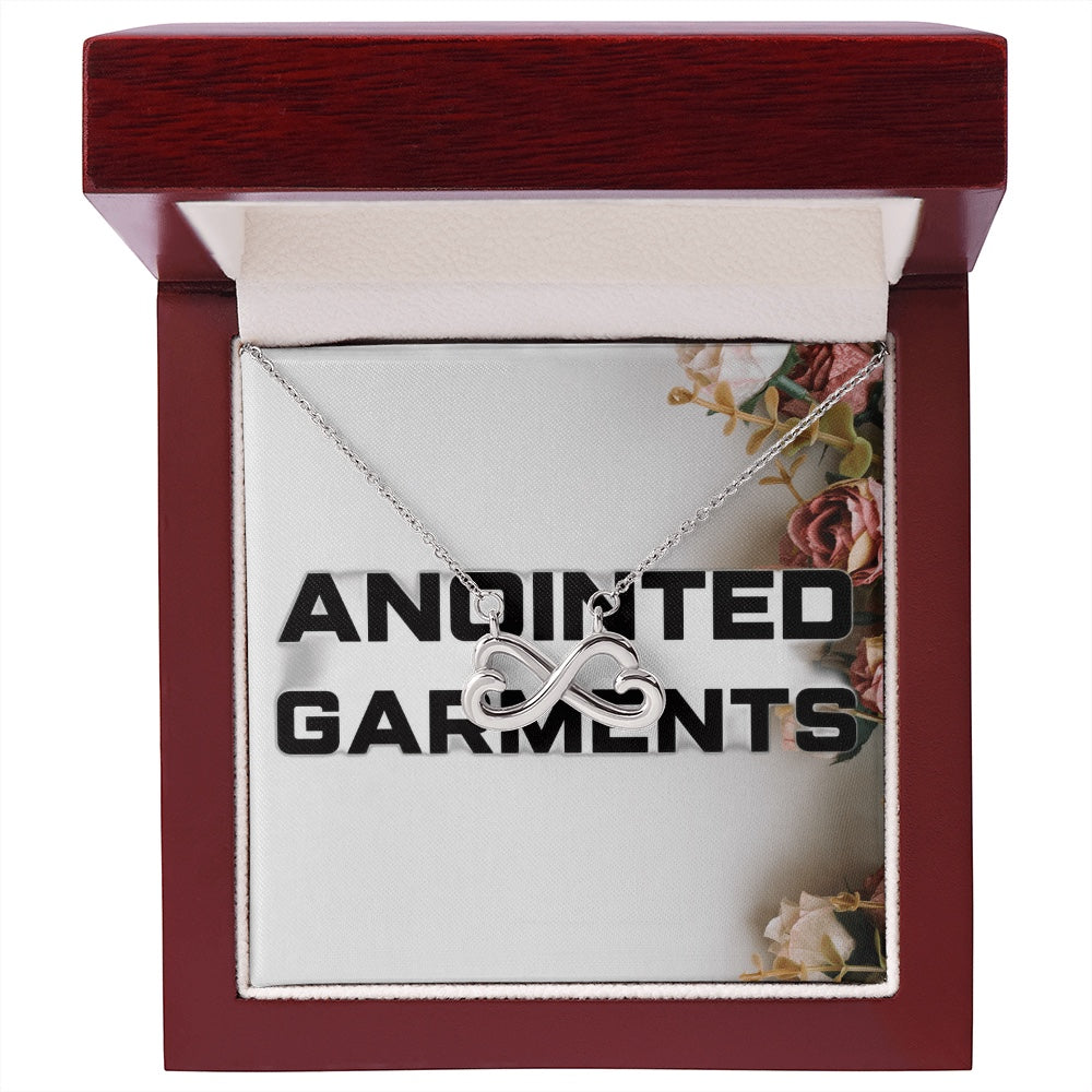 Anointed Garments heart-shaped infinity necklace in white gold finish presented in a polished wooden gift box