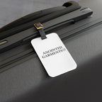 Anointed Garments white luggage tag with black logo attached to a textured black hardshell travel suitcase