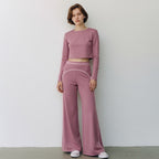 Anointed Garments mauve high-waisted wide-leg trousers with white contrast piping worn by a woman in a matching crop top