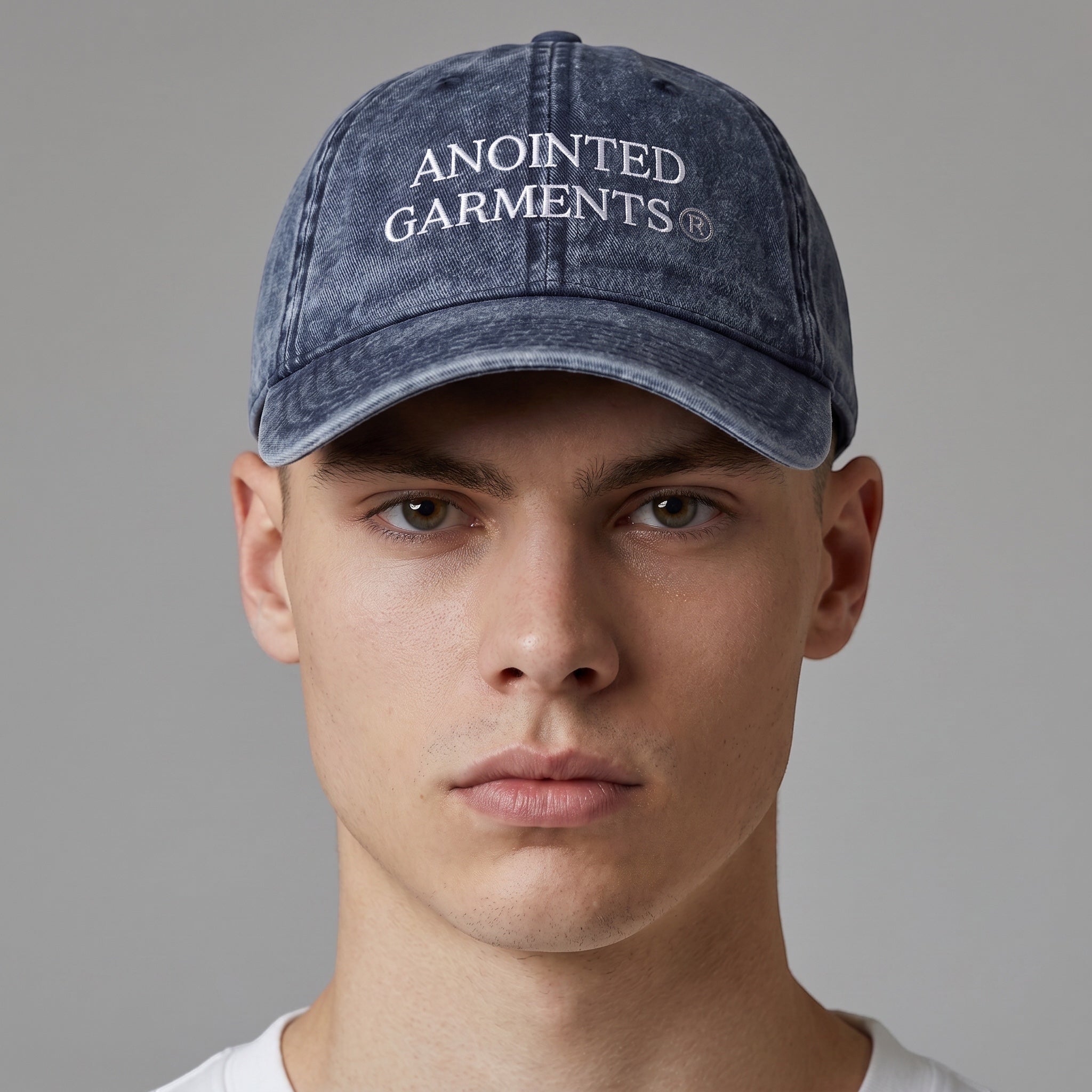 A male model wearing an Anointed Garments navy blue vintage-wash cotton twill baseball cap with white embroidery.