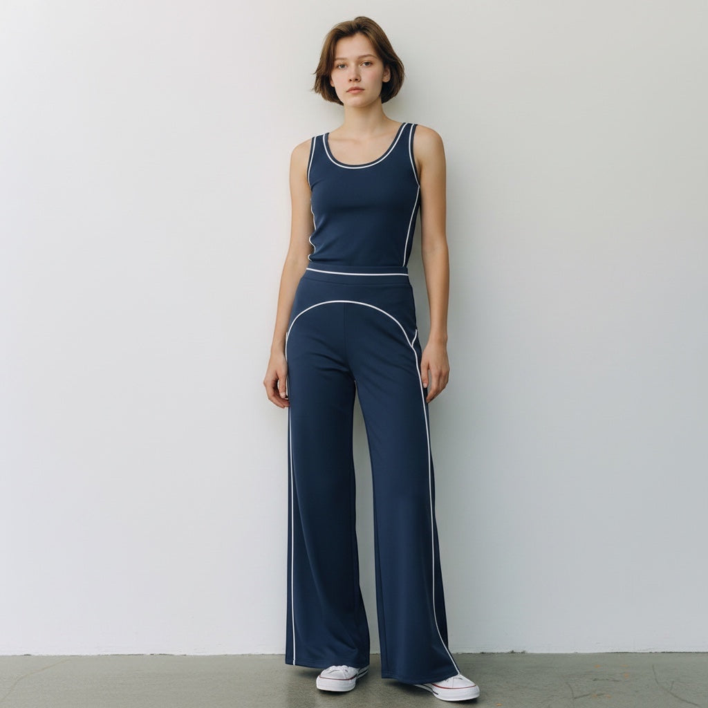 A model wearing Anointed Garments navy blue high-waisted wide-leg trousers and matching tank top with white piping.