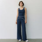 A model wearing Anointed Garments navy blue high-waisted wide-leg trousers and matching tank top with white piping.