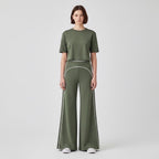 Model wearing Anointed Garments olive green high-waisted wide-leg trousers with white contrast piping and matching top