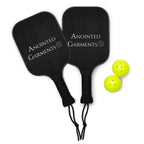 Anointed Garments pickleball set with two black wooden paddles and two bright yellow plastic balls.