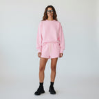 Model wearing Anointed Garments pink fleece lounge shorts with matching sweatshirt, drawstring waist, and side pockets.
