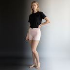 Model wearing Anointed Garments light pink high-waisted athletic shorts with crossover waistband and side pockets.