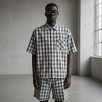 Anointed Garments model wearing a grey and white plaid short sleeve button down shirt with a chest pocket.