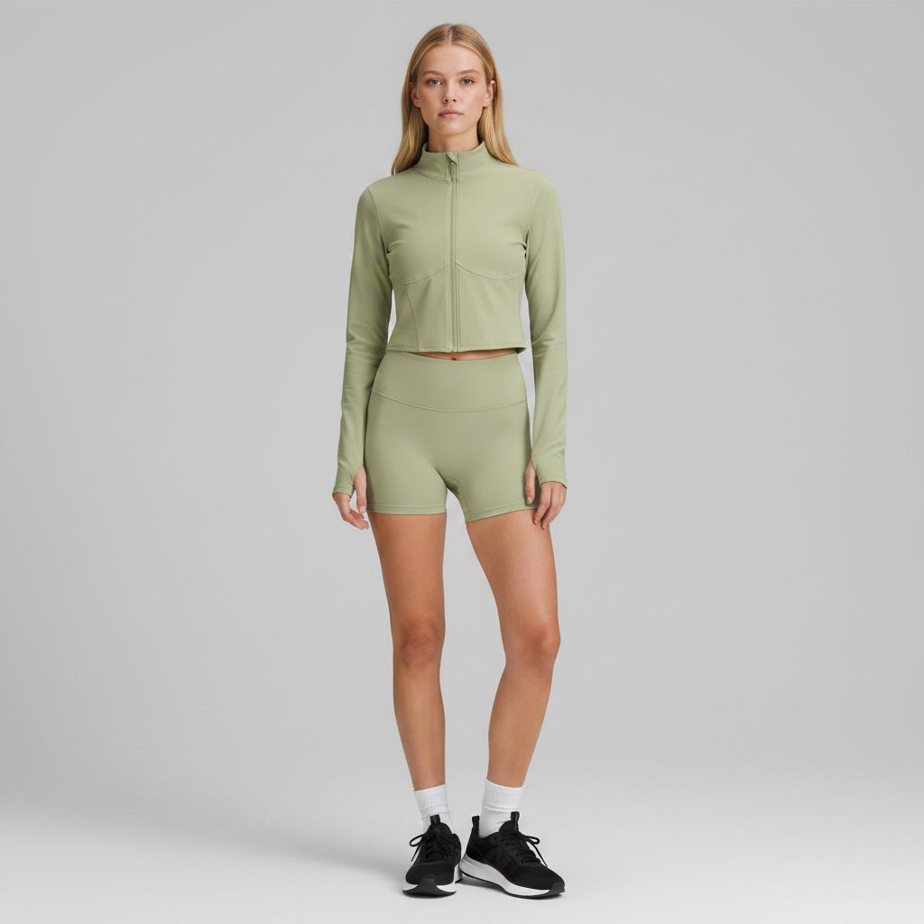 Model wearing Anointed Garments sage green cropped long sleeve mock neck zip up jacket with matching athletic shorts.