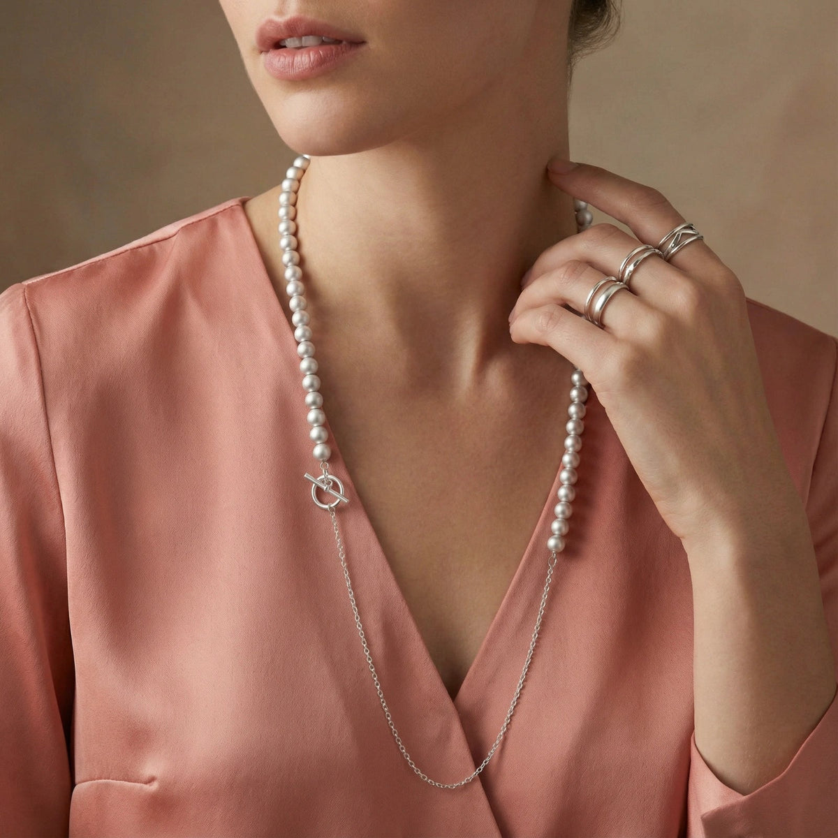 Anointed Garments graduated sterling silver sphere necklace worn by a woman in a pink silk top with silver rings.
