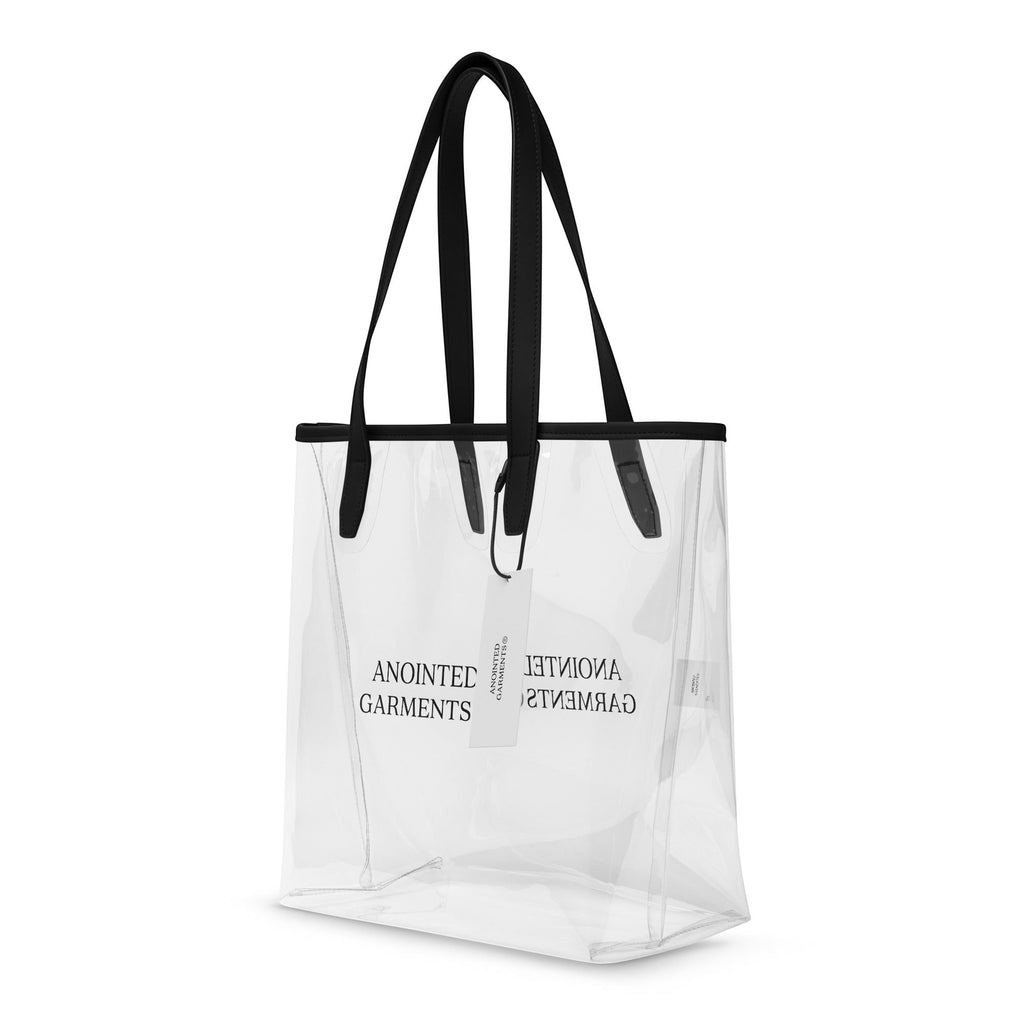 Anointed Garments transparent TPU tote bag with black trim and shoulder straps, featuring minimalist brand logo.