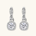 Anointed Garments twisted infinity halo moissanite earrings in platinum-plated 925 sterling silver with round-cut stones.