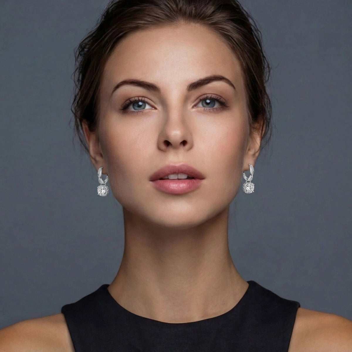 Anointed Garments twisted infinity halo moissanite earrings in platinum-plated sterling silver worn by a woman.
