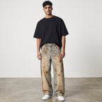 Model wearing Anointed Garments relaxed fit barrel-leg denim jeans with a vintage wash and distressed detailing.