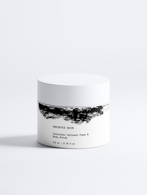 Anointed Garments Icelandic Volcano Face & Body Scrub in a white jar with black volcanic sand texture graphic design.